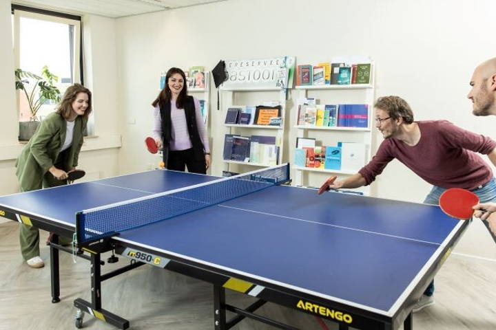 Actiefoto van pastoor bv medewerkers die aan het pingpongen zijn